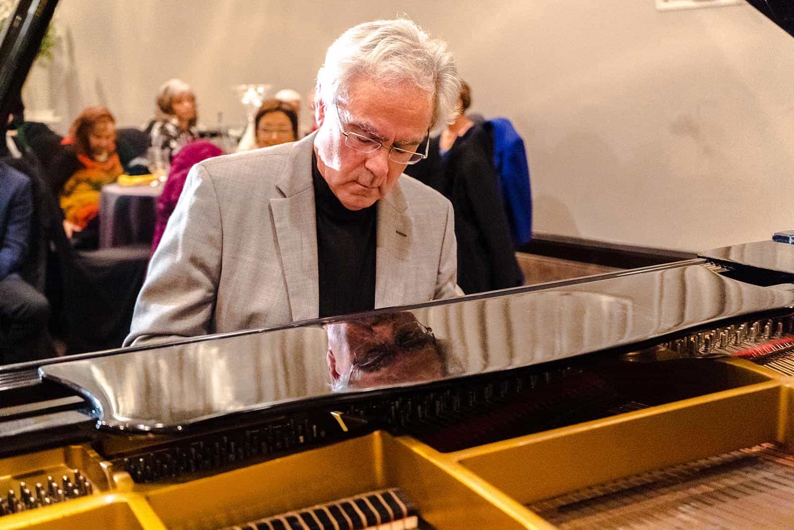 Siegfried Tepper behind the keys of an open baby grand piano.