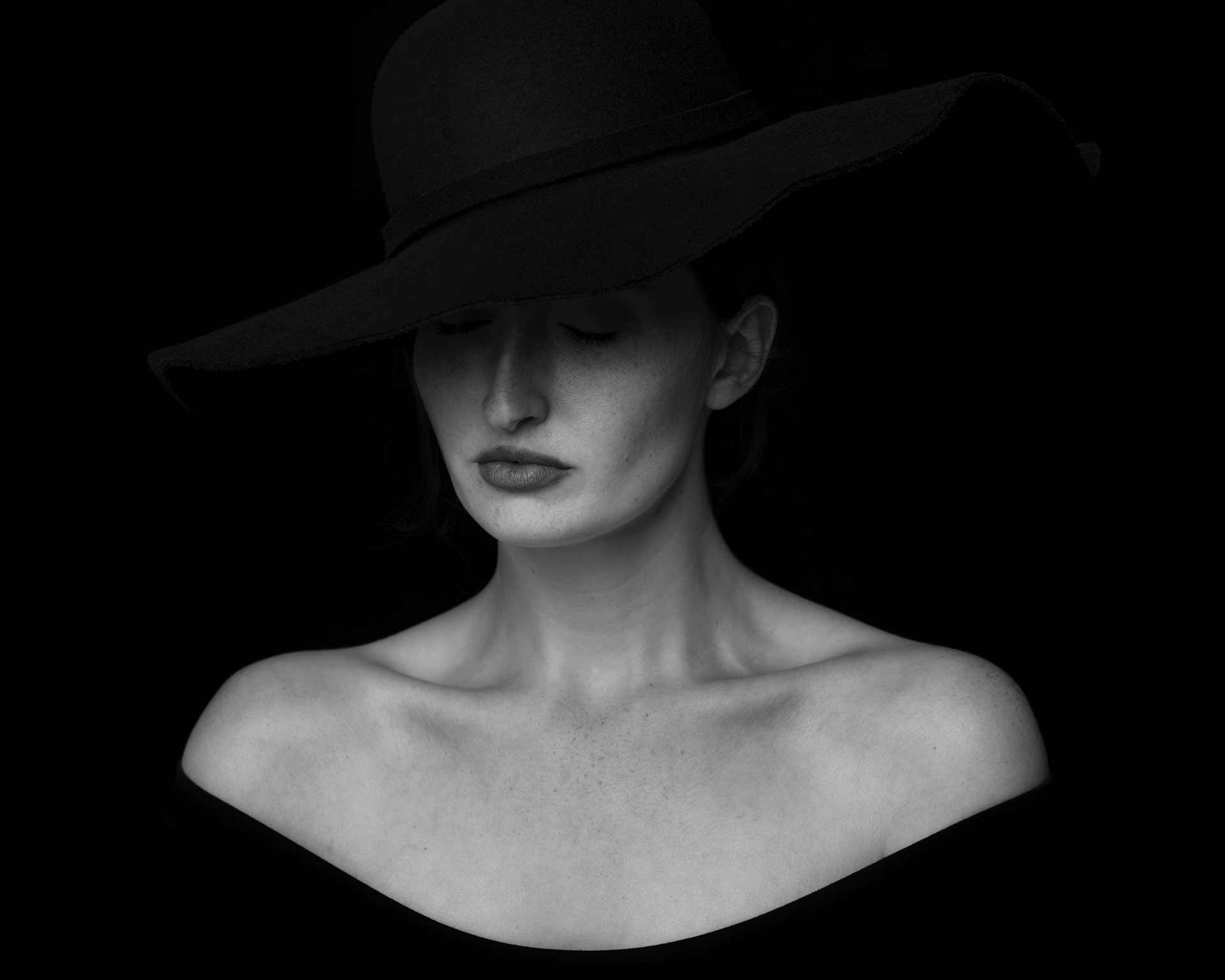 A woman wearing a hat, draped in shadows.