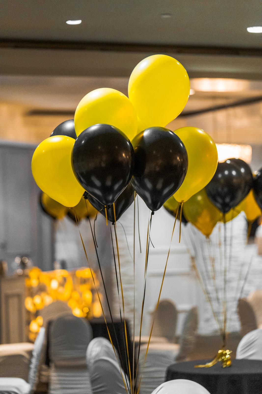 A group of yellow and black balloons floating above a table