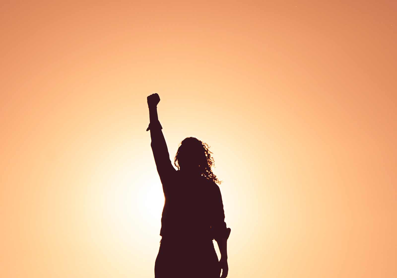 A woman stands cheering in the sun